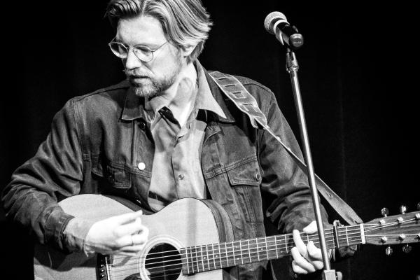 Male performer singing and playing guitar.