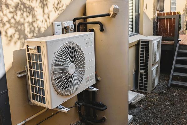 Hot water heat pump split unit installed at a home. Reverse cycle air conditioning system in the background.