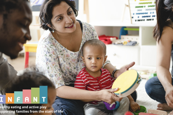 mother and baby playing the tambourine in a group with other parents and babies