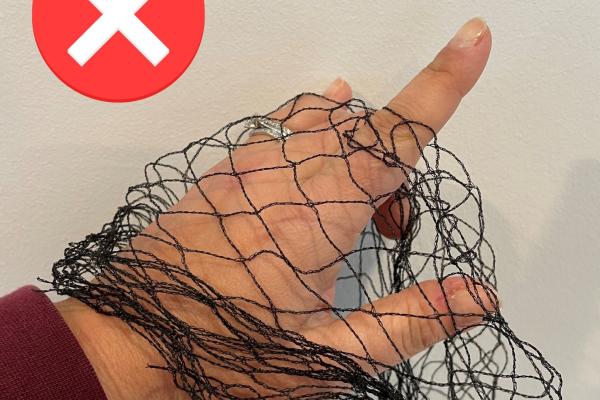 Illegal fruit tree netting, showing a finger poking through the wide mesh