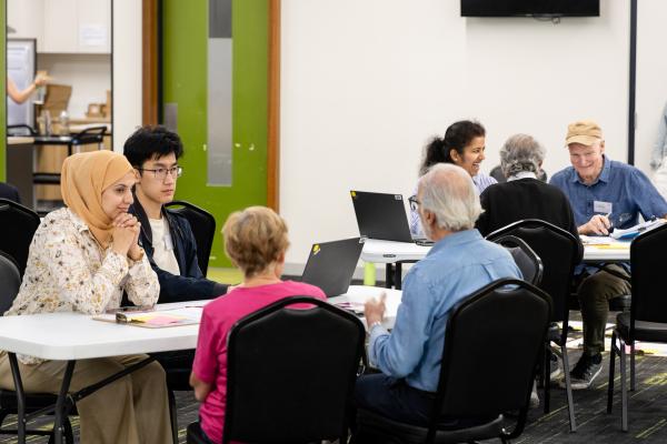 Image of community panel members sitting at tables in small groups 