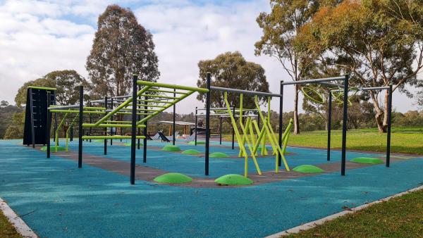 A large obstacle course with an aqua coloured astro turf surface in a bushy park setting