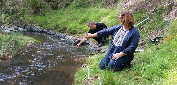 Man and woman by river testing water 