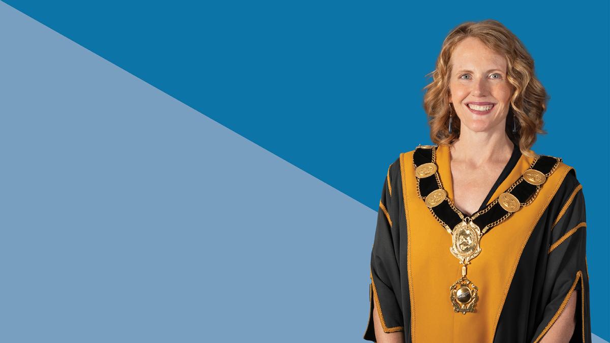 Cr Deirdre Diamante smiling, wearing the mayor robes. A blue background.