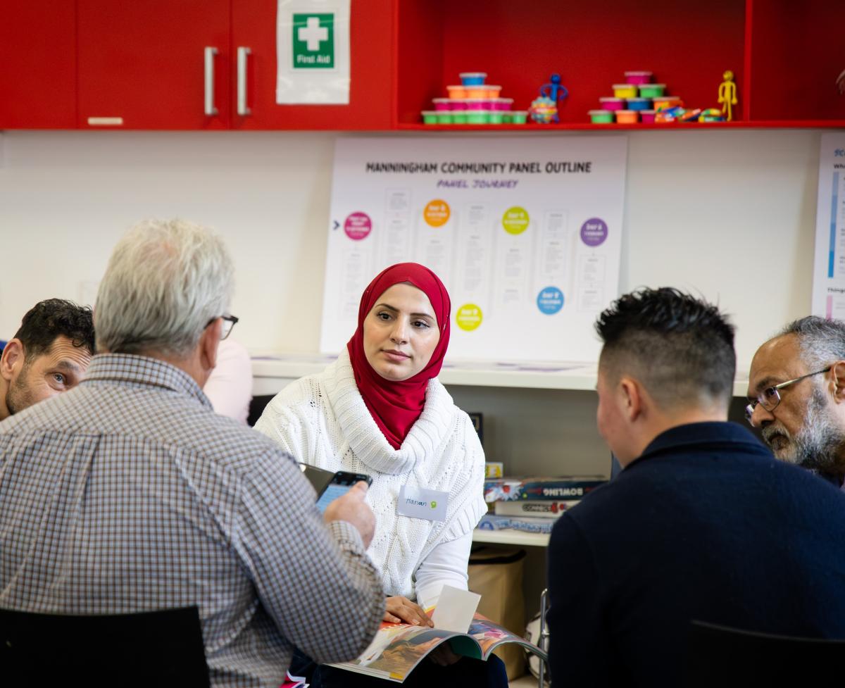woman speaking to four men in consultation, the men have their backs to the camera