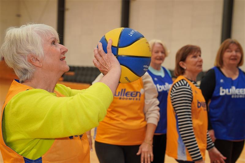 Older woman with a basketball in her hand poised to take a shot
