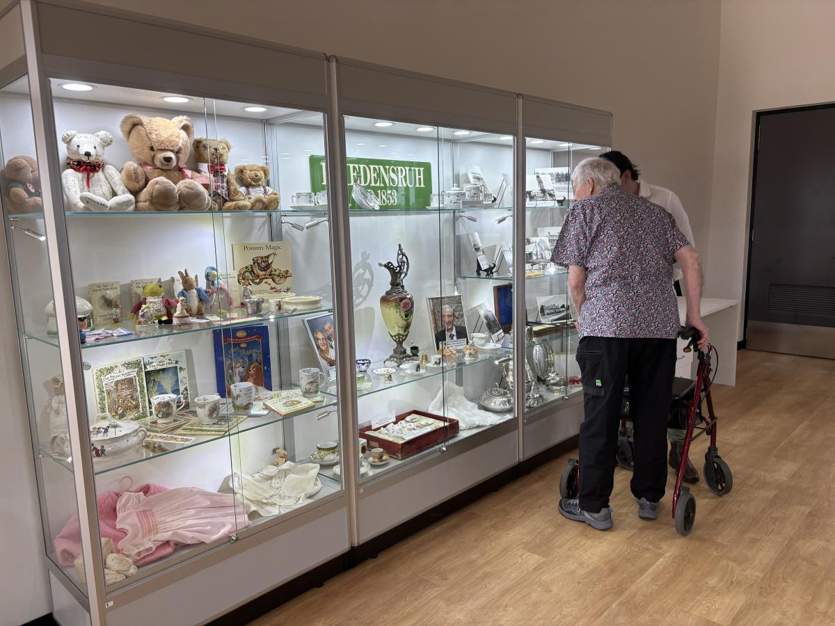 Two people, one using a walker, looking at historical items in a glass cabinet in the new visitor centre