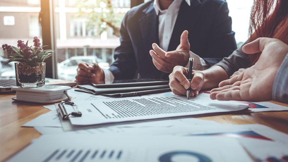 stock image of a closeup of the hands of three people signing a document