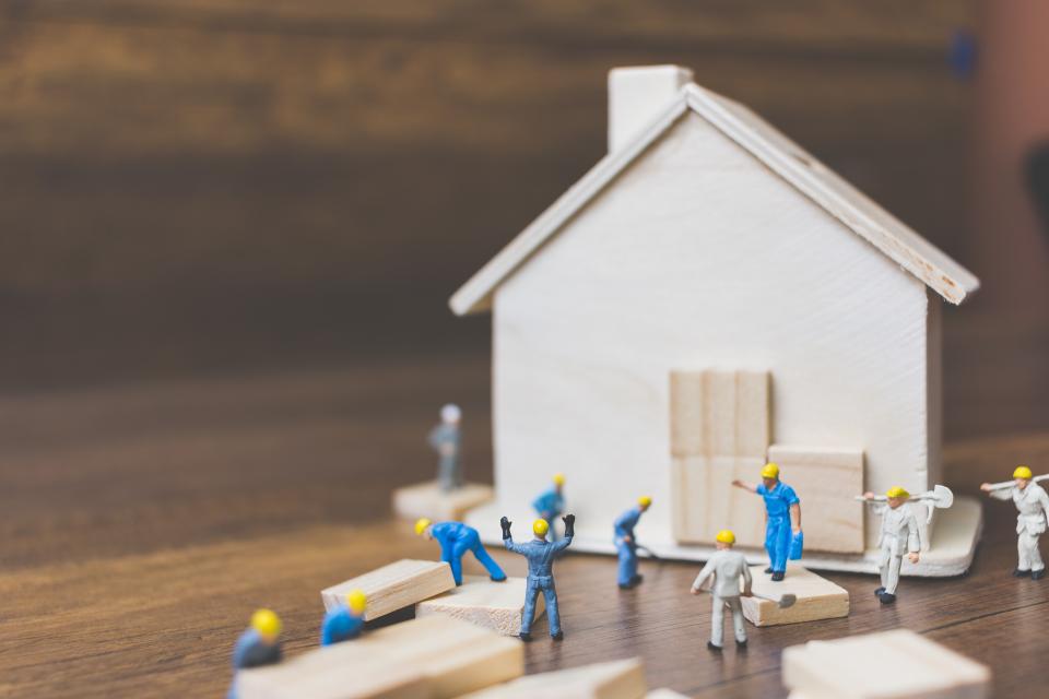 Stock photo of model figures building a house
