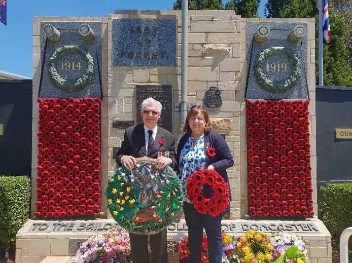 man and woman stand in front of Doncaster RSL war memorial holding wreaths