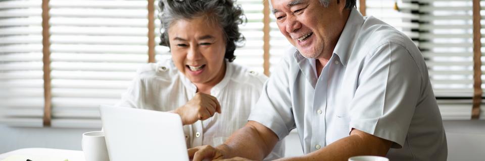 Older Asian couple in front of laptop