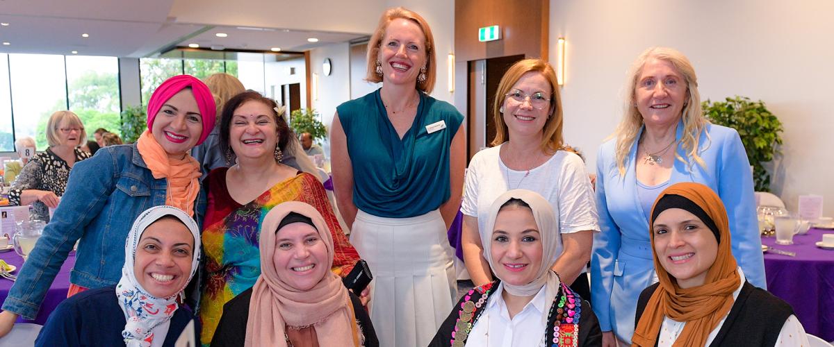 Councillor Deirdre Diamante and attendees at the 2022 International Women’s Day event, which had the theme #BreakTheBias. The women are smiling and sitting and standing around a table with a purple table cloth.