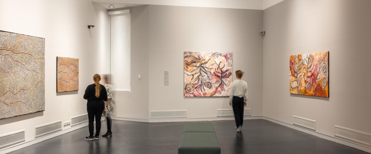 Three women in the Manningham Art Gallery viewing paintings from the Painted Country exhibition.
