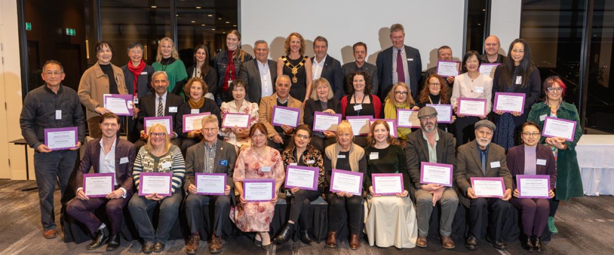 A formal photograph of Councillors and all the grants recipients in a group with the grants recipients holding their certifcates of appreciation