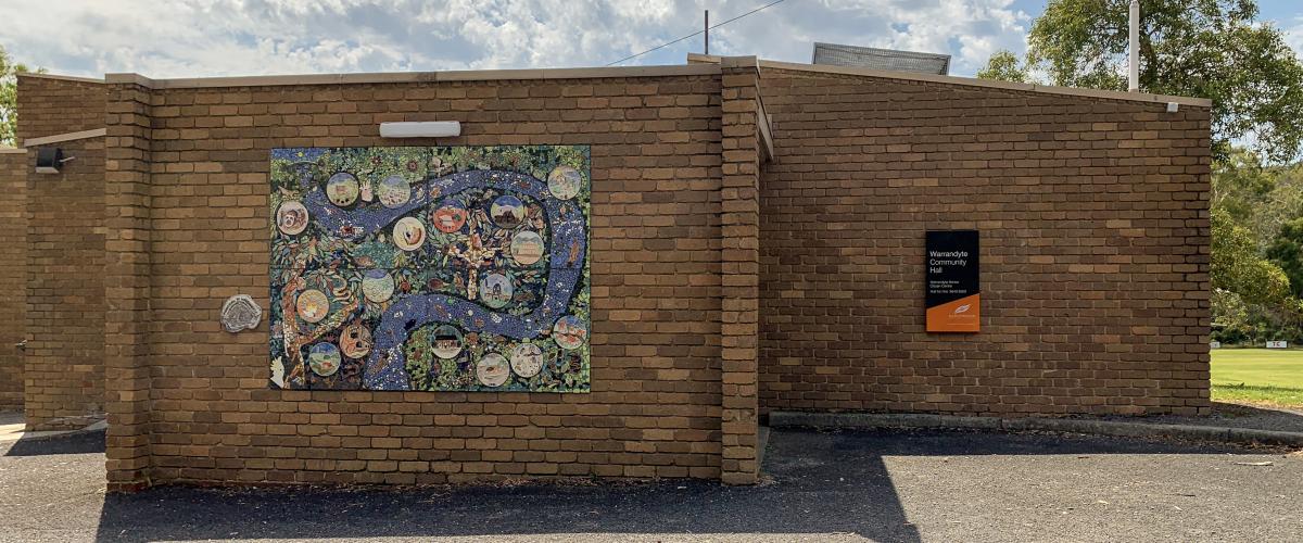 A brown-brick building with a large mosaic artwork on the wall.