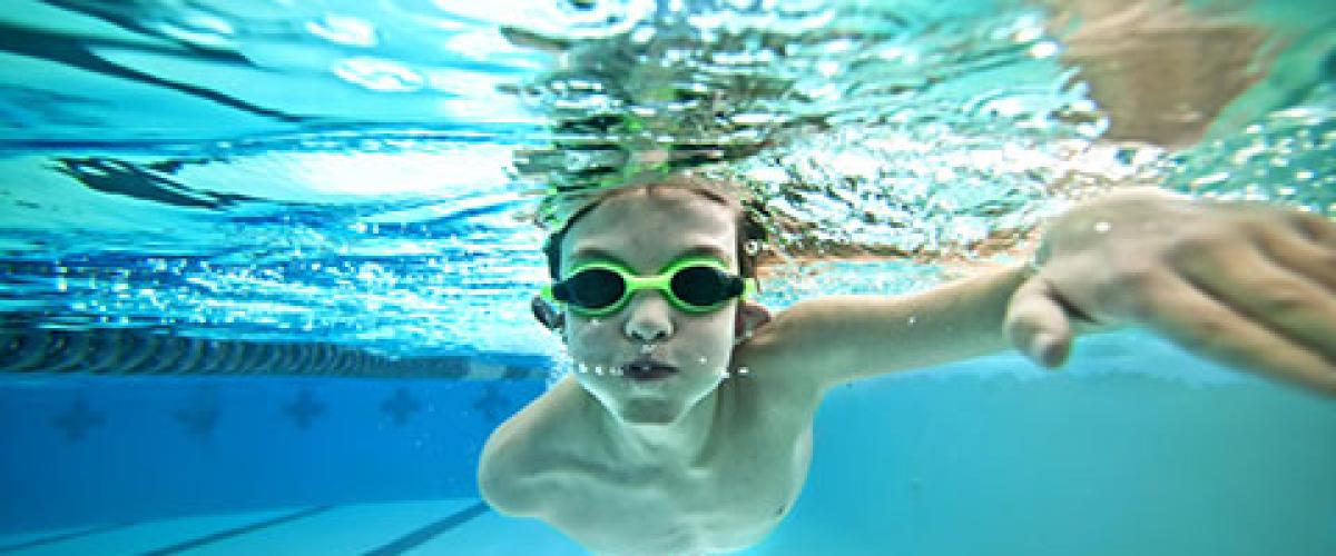 underwater photo of boy with googles swimming