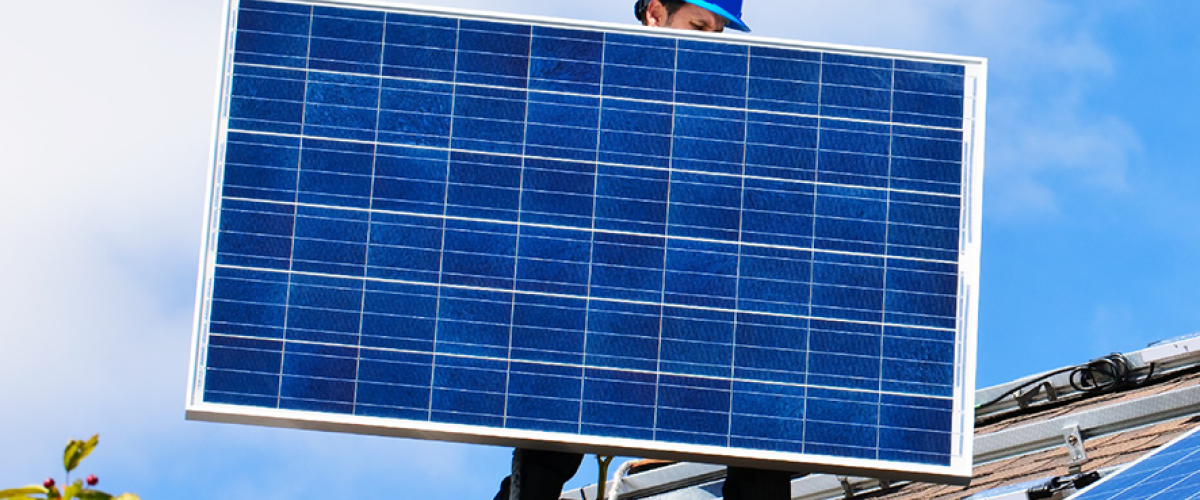 Man placing a solar panel on a roof