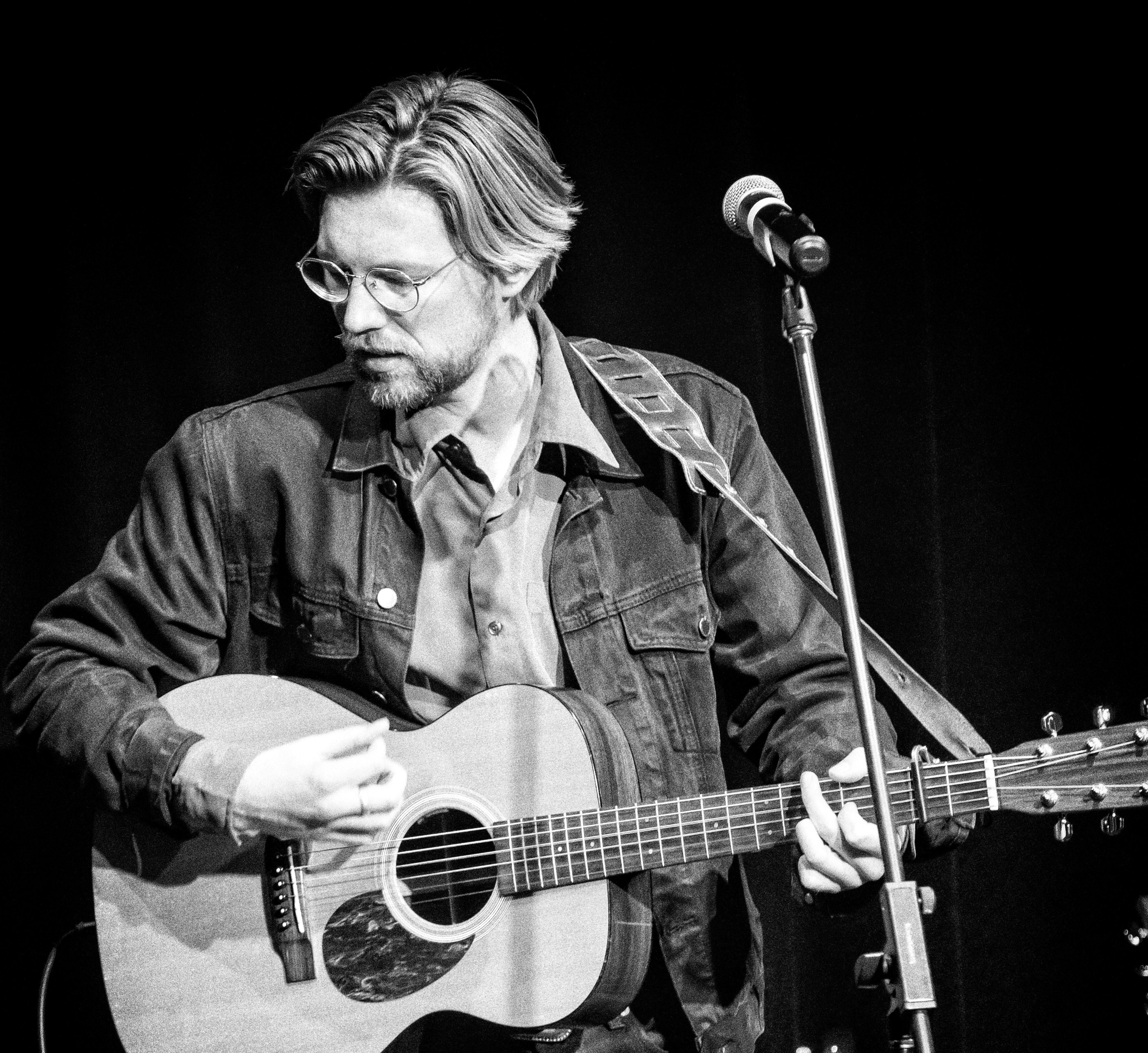 Male performer singing and playing guitar.