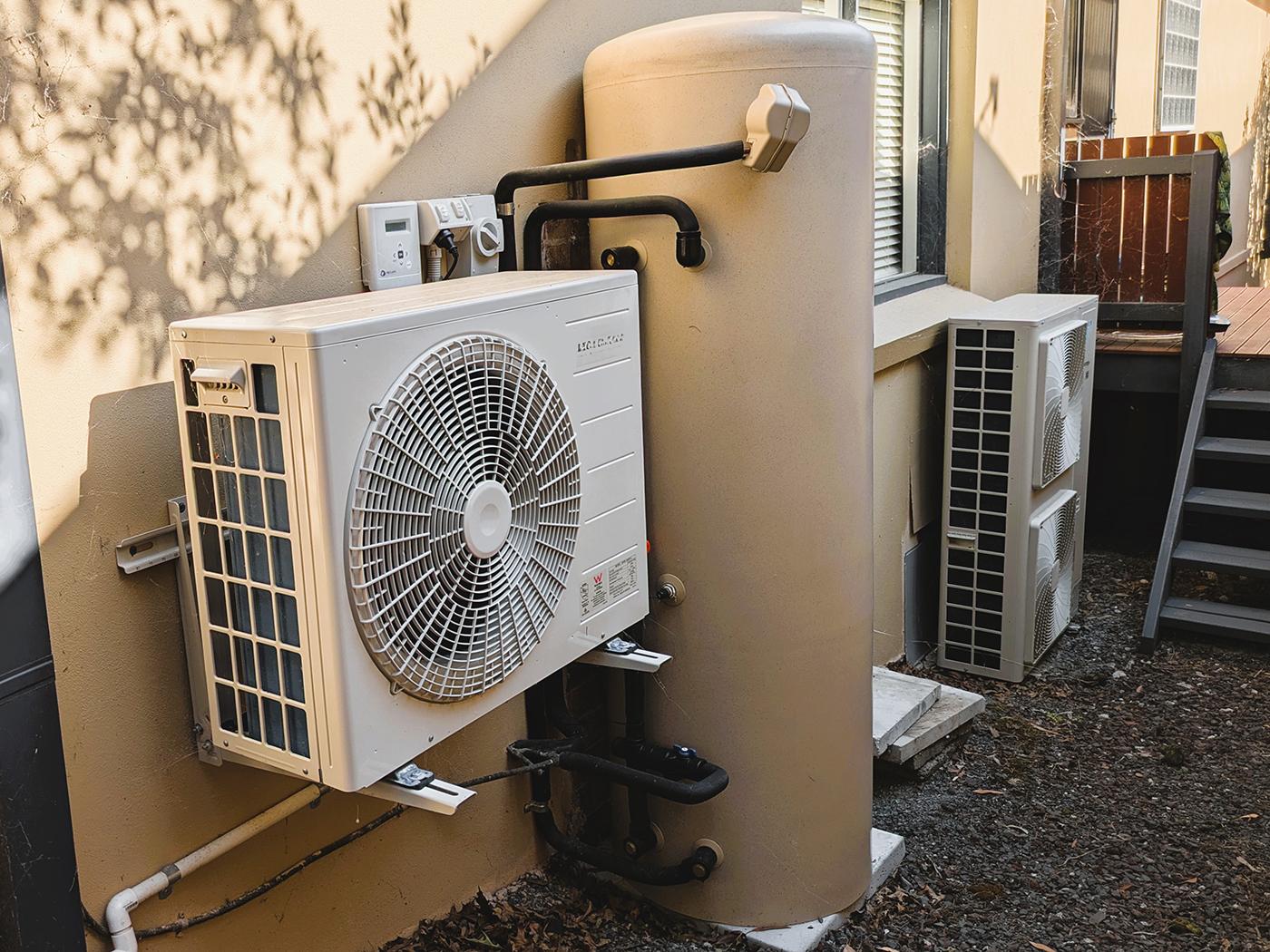 Hot water heat pump split unit installed at a home. Reverse cycle air conditioning system in the background.