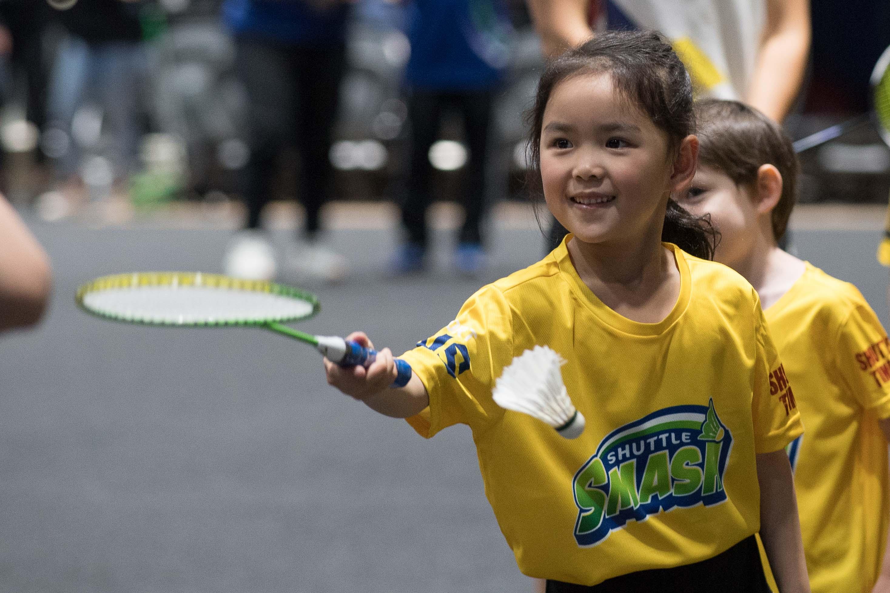 A young girl participating in Shuttle Smash Badminton wearing a yellow t-shirt