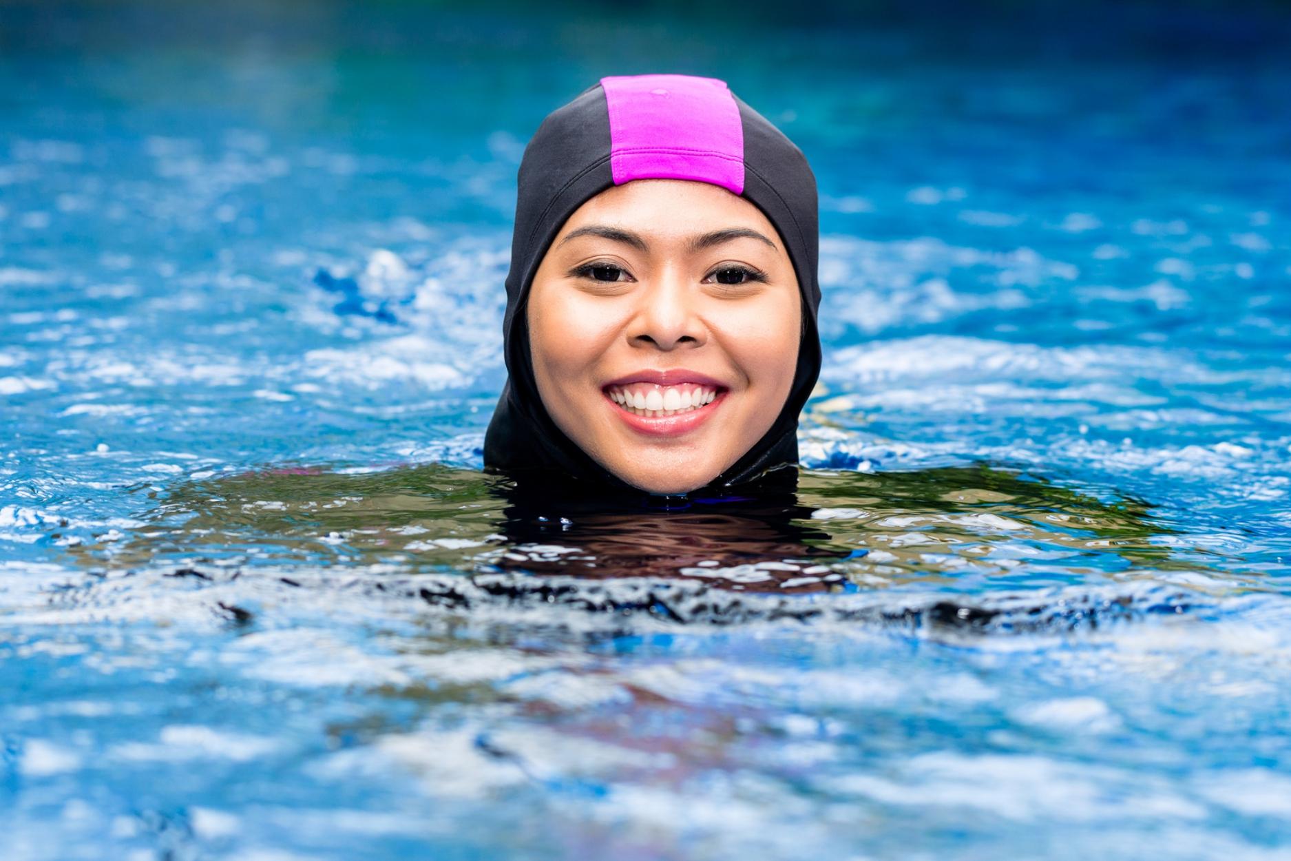 Young woman in a pool wearing head covering