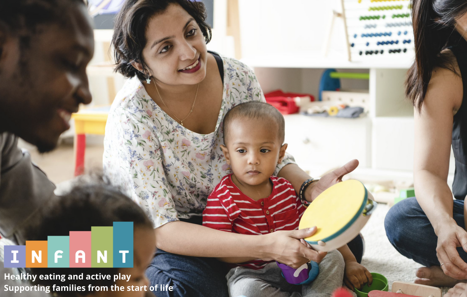 mother and baby playing the tambourine in a group with other parents and babies