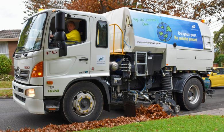 street sweeper sweeping up leaves on road