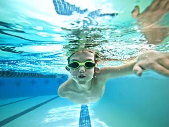 underwater photo of boy with googles swimming