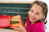 Young girl holding a lunch box with sandwich and carrots 