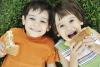 Two children laying on the ground eating sandwiches 