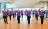 A group of dancers wearing purple tops, black dressings and pants and hats, from the Seniors Happy Life group, performing at the Manningham Function Centre.